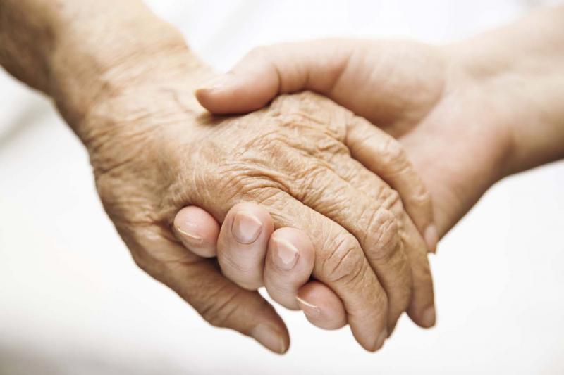 An older person holding hands with a younger person