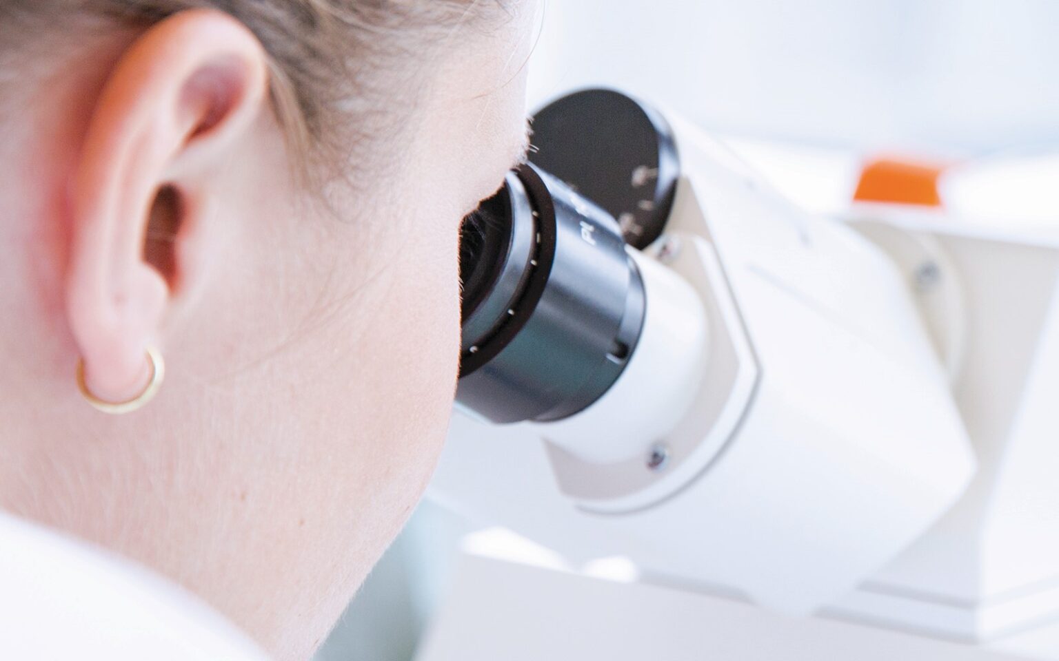 female laboratory worker looking into microscope